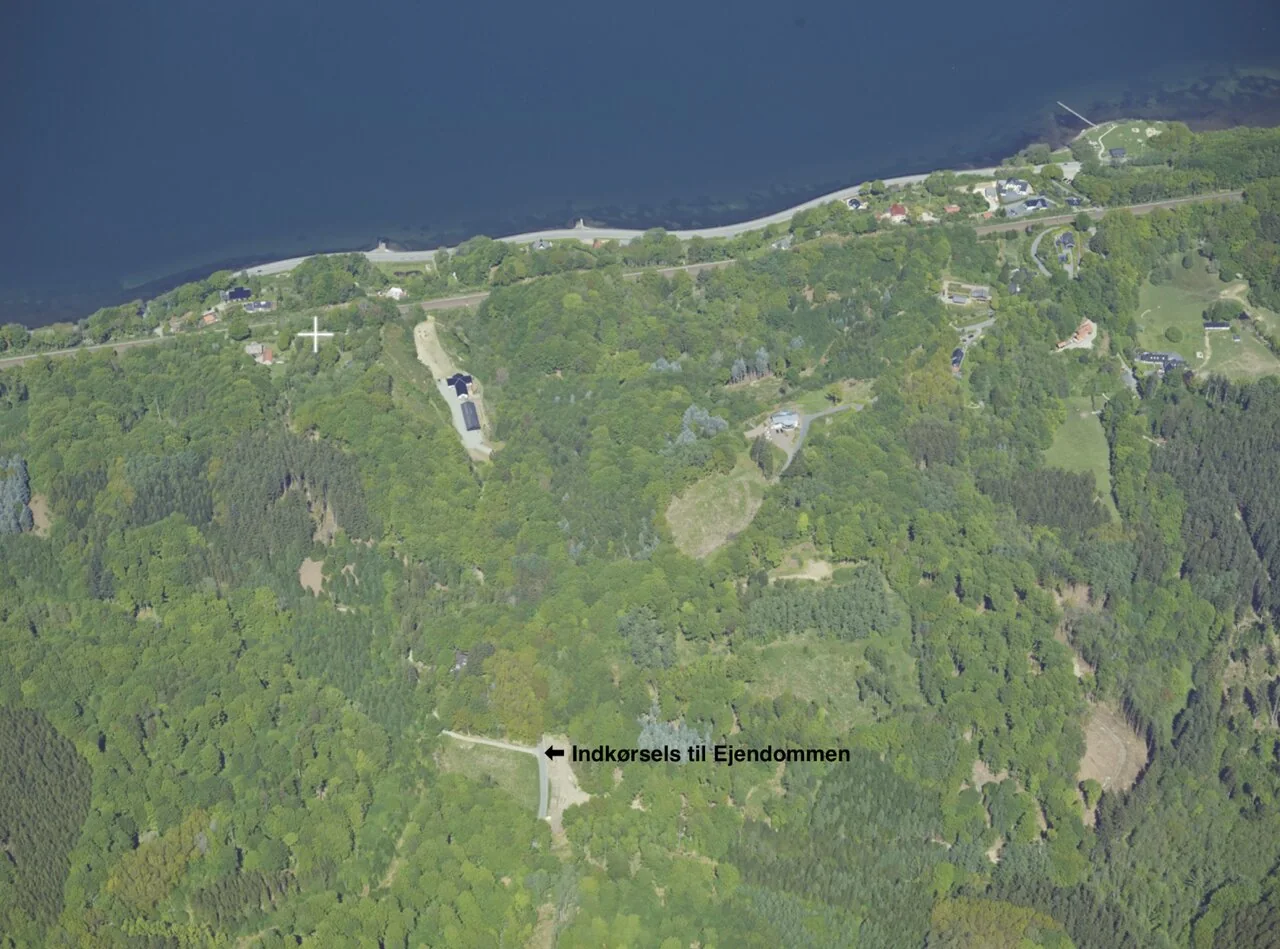 Luftfoto over ejendommen i Munkebjergskoven med Vejle Fjord i baggrunden og indkørslen markeret