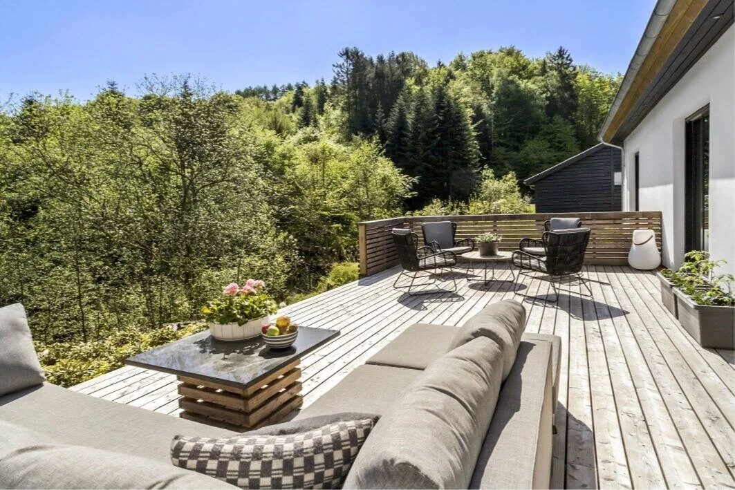 Terrasse med loungemøbler og udsigt over skov og fjord